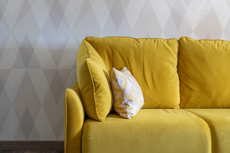 spring design trend yellow couch in front of gray argyle wallpaper
