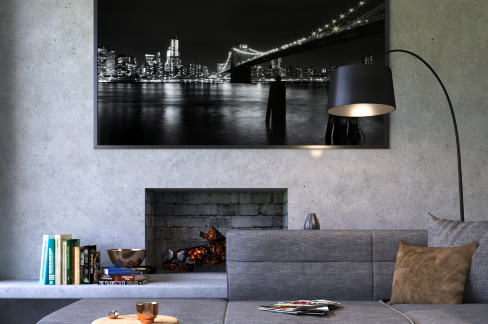 Monochromatic color palette in living room with a gray couch, gray walls, B&W print on the wall, a black lamp, and a black fireplace