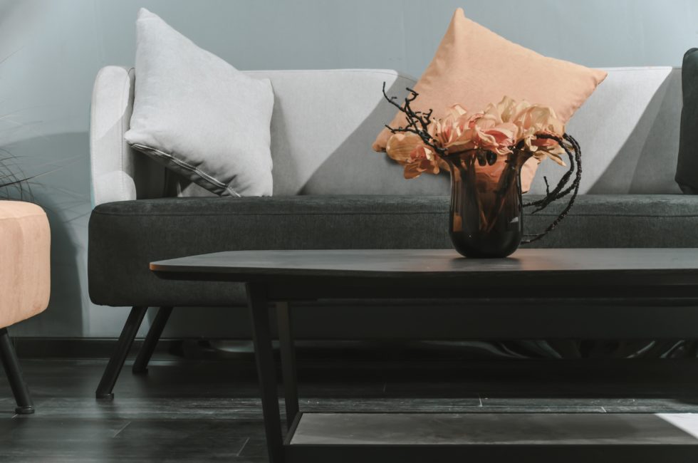 gray couch and a dark oval coffee table styled with a floral arrangement in a vase