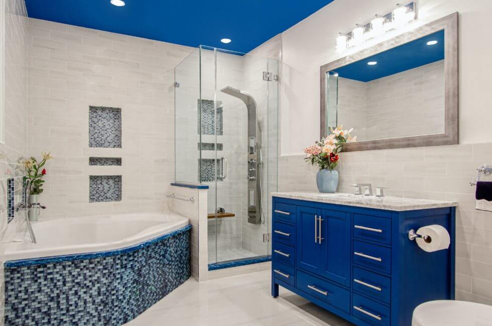 white bathroom with blue ceiling, cabinets, and tub to showcase colors to paint a bathroom