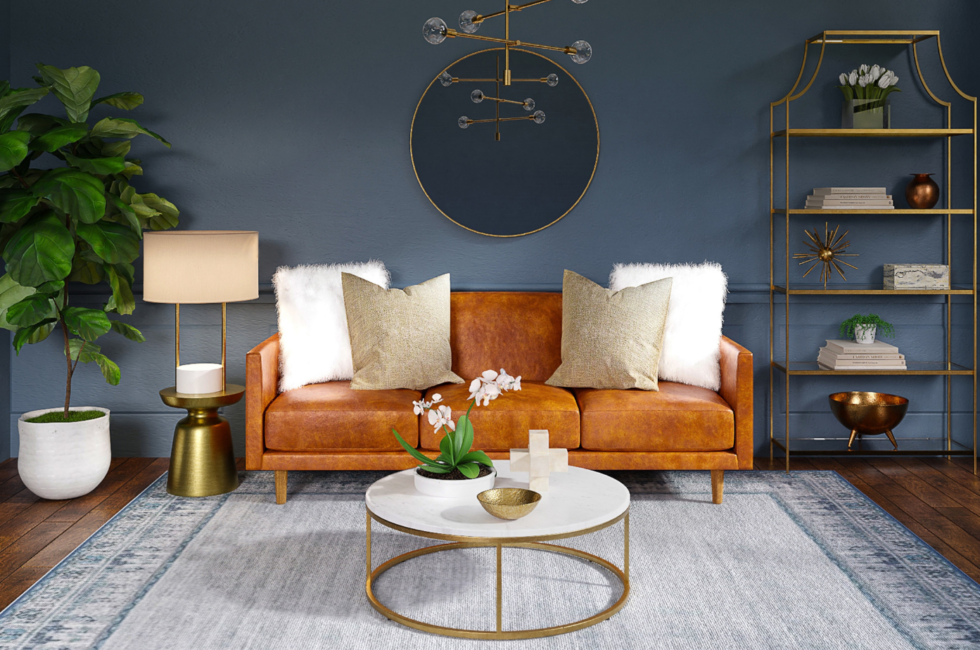 living room reflecting interior design trends of 2022 such as a teal wall with a round mirror as well as a brown sofa, white and gold round coffee table, gold accent table and bookshelf, and a fiddle leaf fig in the corner