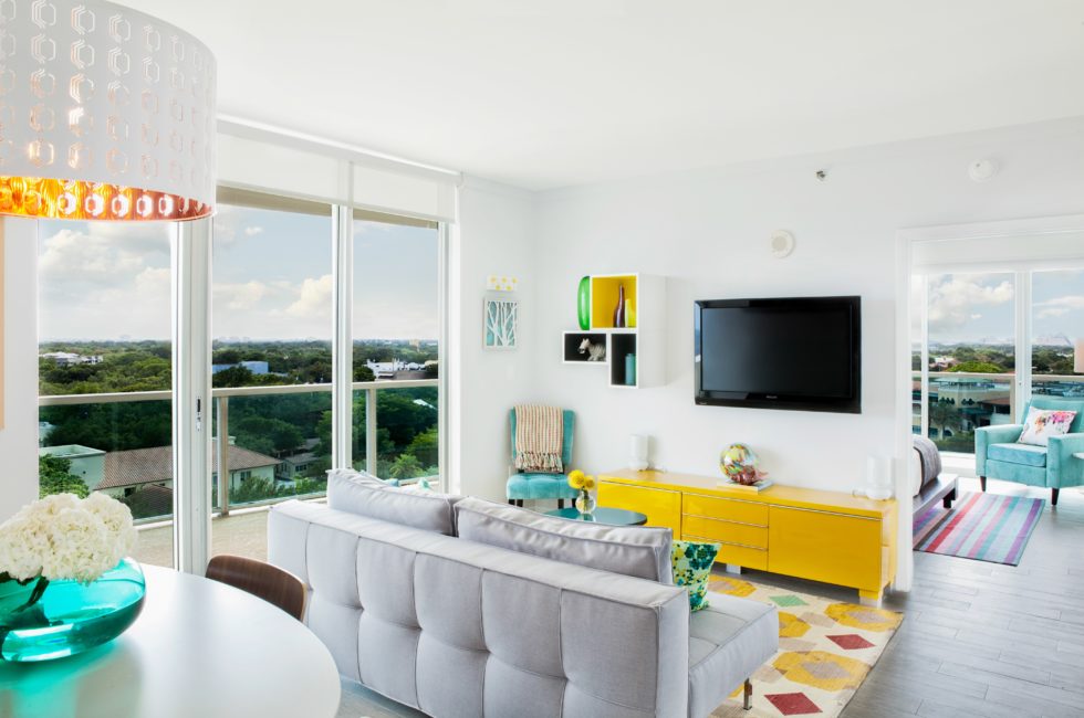 interior design ideas for your condo in Florida featuring a white living room with a light gray couch and a bright yellow console table