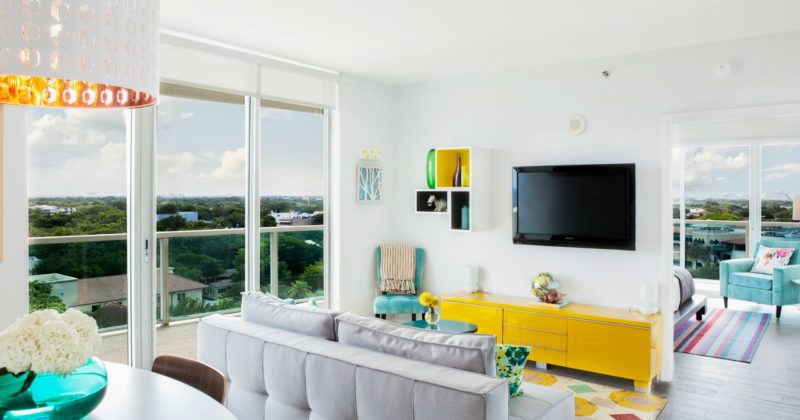 interior design ideas for your condo in Florida featuring a white living room with a light gray couch and a bright yellow console table