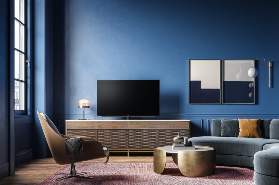 interior design tips implemented in a dark blue living room with a semi-round couch, metal coffee table, and an accent chair