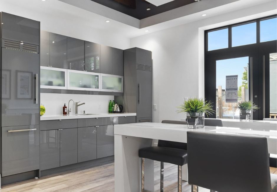 Lacquer furniture featured in a white kitchen with light wood flooring, gray cabinets, a white counter-height table with dark gray chairs